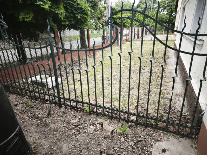 Kopott, fakó festésű kerítésszakasz épület mellett, felújítás előtt